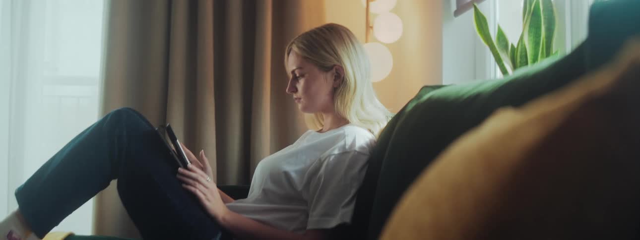 Woman sitting on the sofa in the living room and using a tablet