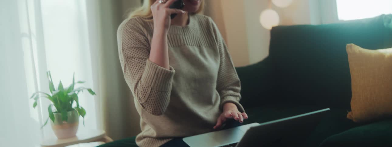 A woman talking on the phone and using her laptop in a room