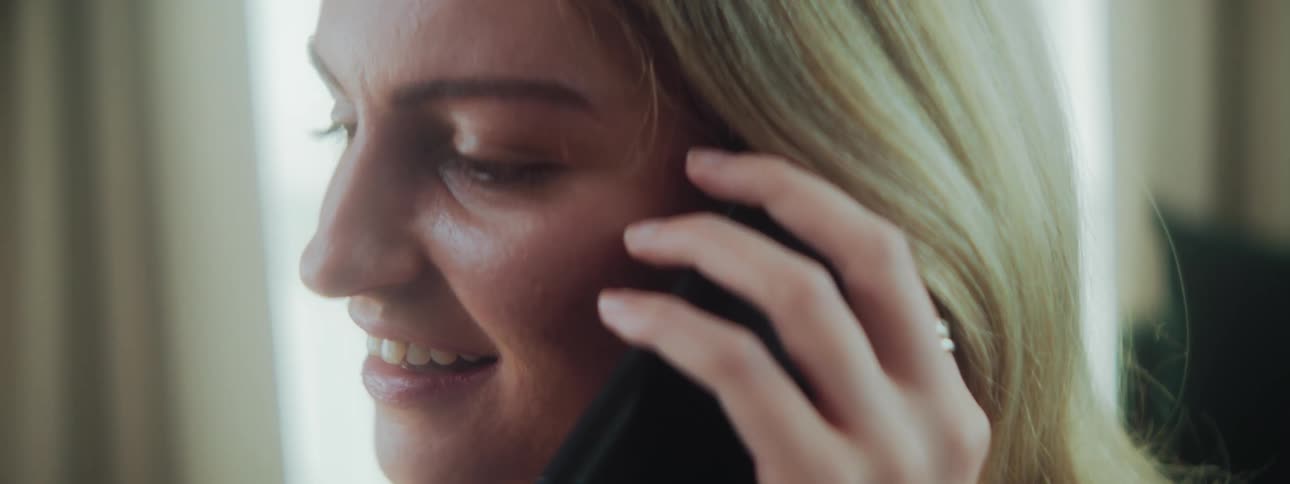 A woman smiles after answering the phone