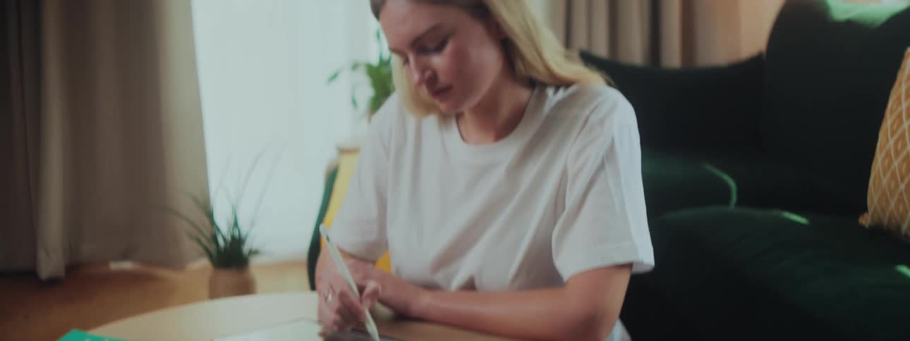 A woman is drawing on the tablet at home