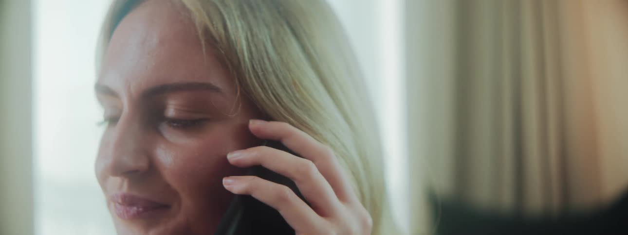 A woman is smiling while talking on the phone