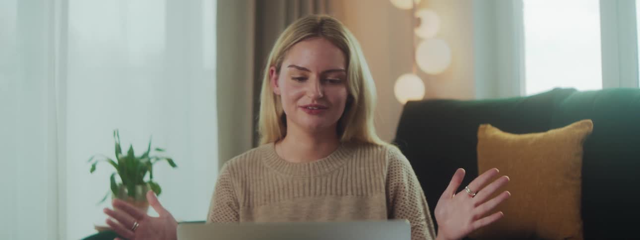 Happy blonde woman talking in front of a laptop