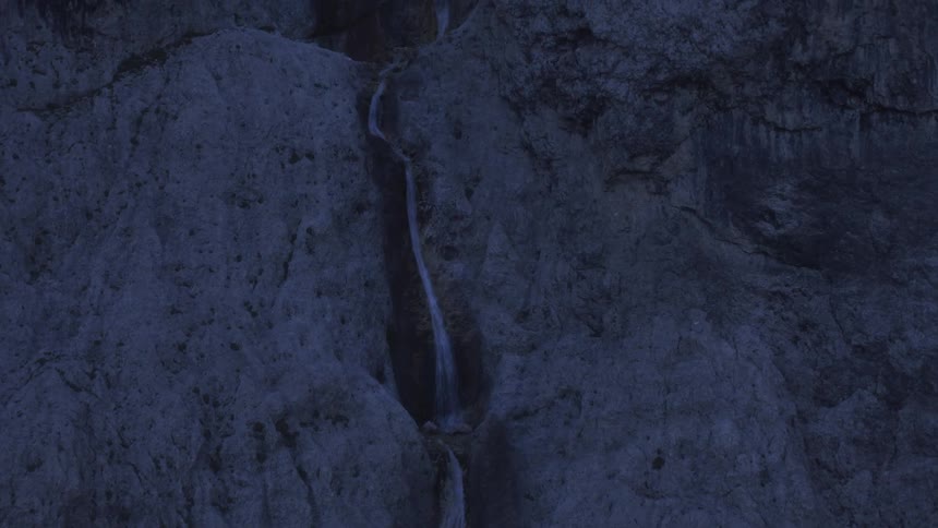 A stream flows down a mountainous rock during sunrise