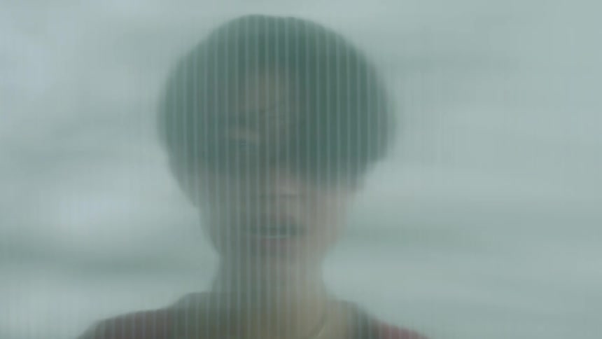 A man breathes onto a bathroom glass making it blurrier and foggier