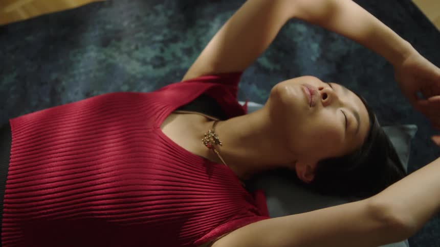 A woman lying on a pillow on the floor stretching her arms upward