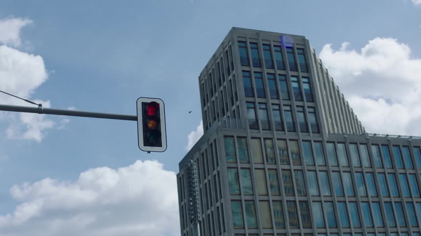 A traffic light changes from red to yellow to green in front of a modern building