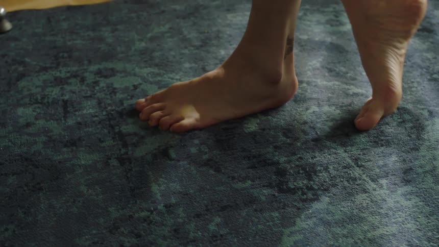 Bare feet move rhythmically on a textured rug