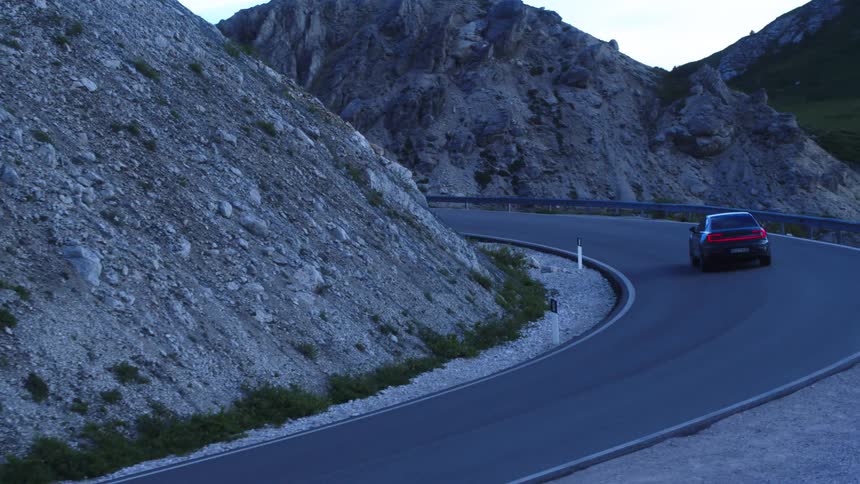 A car in motion on a road beside mountains