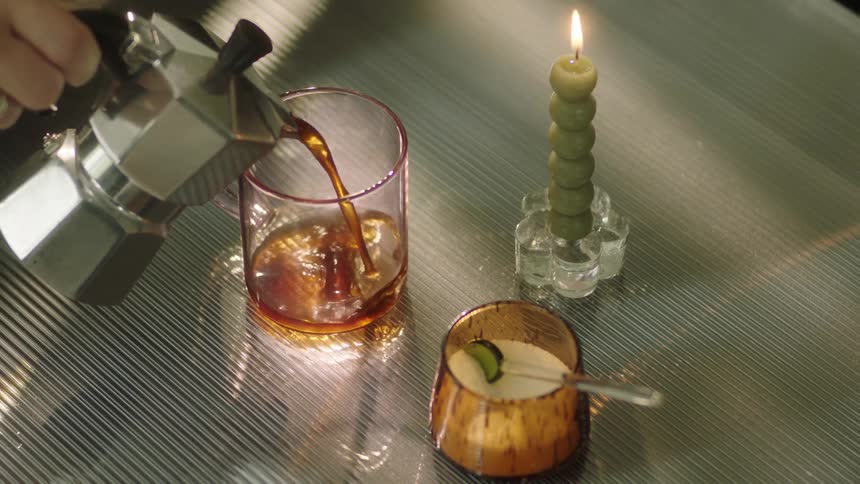 A person is pouring a drink into the mug