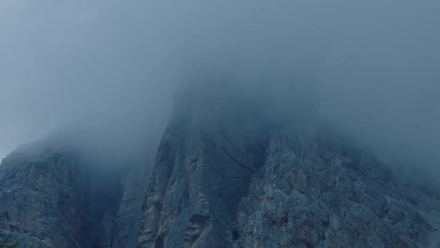 Fogs rolls over a steep rocky mountain