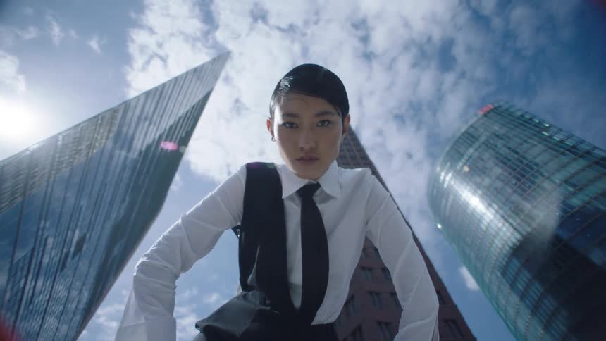 In a downtown city a woman is standing next to buildings