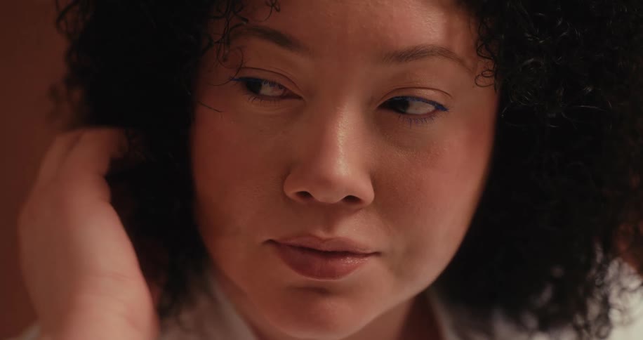 A woman gently touching her curly hair