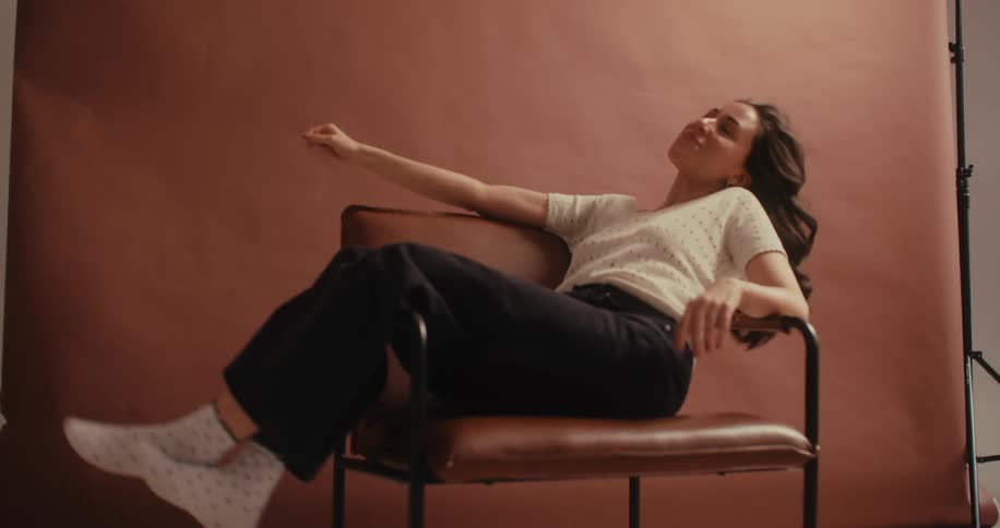 A footage of a lady sitting and posing in the studio