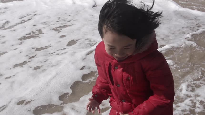 Little girl runs on the sand beach by the ocean