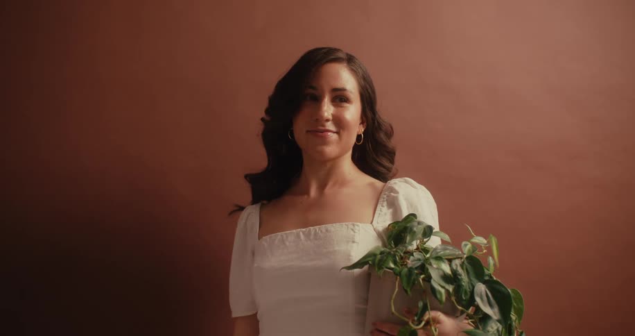 A portrait image of a lady holding a green plant