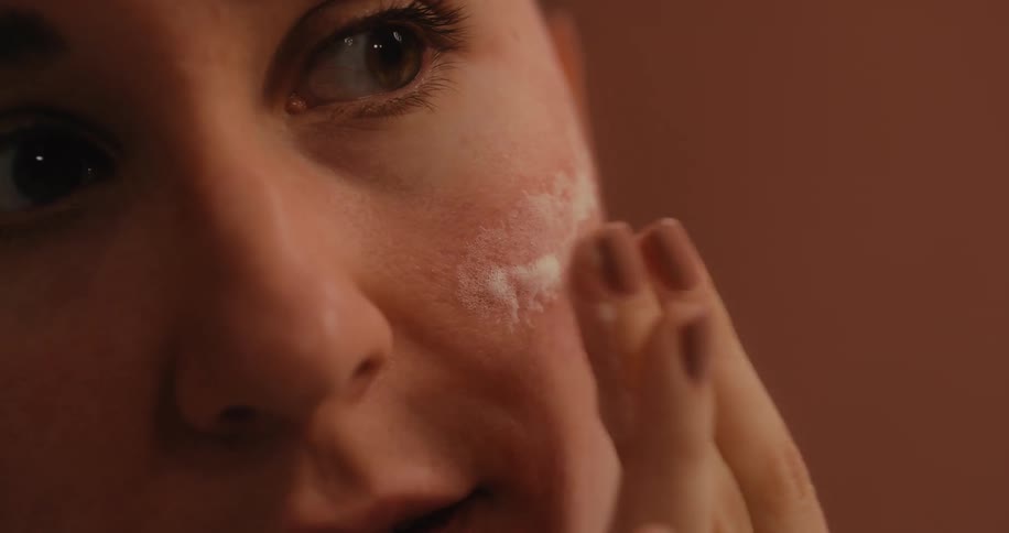 A young woman applying makeup on her face
