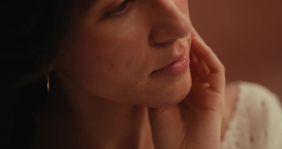 Close up of a woman with her hand on her neck and face