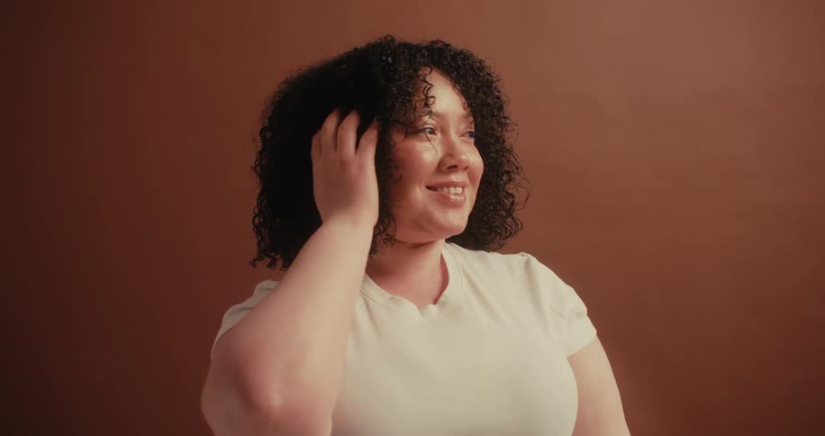 A woman touching her curly hair and smiling