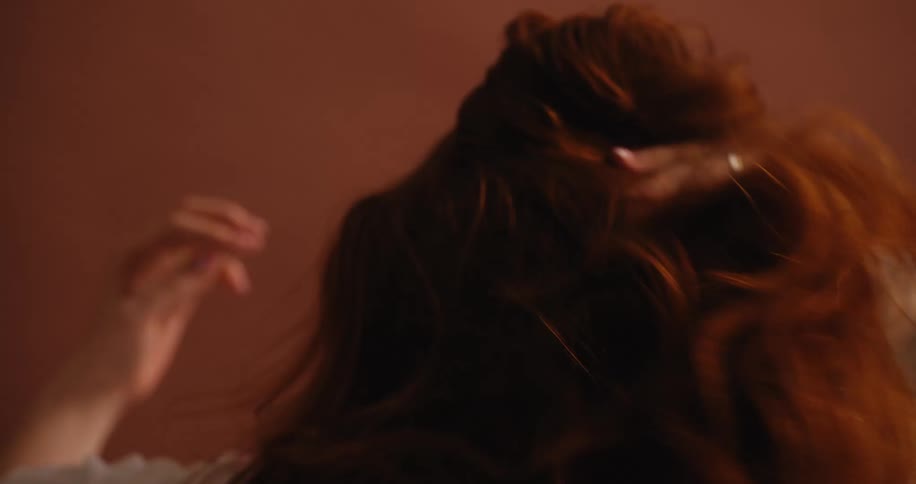 A redhaired woman caressing her long hair
