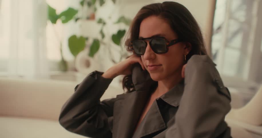 Woman with sunglasses posing in a long gray coat