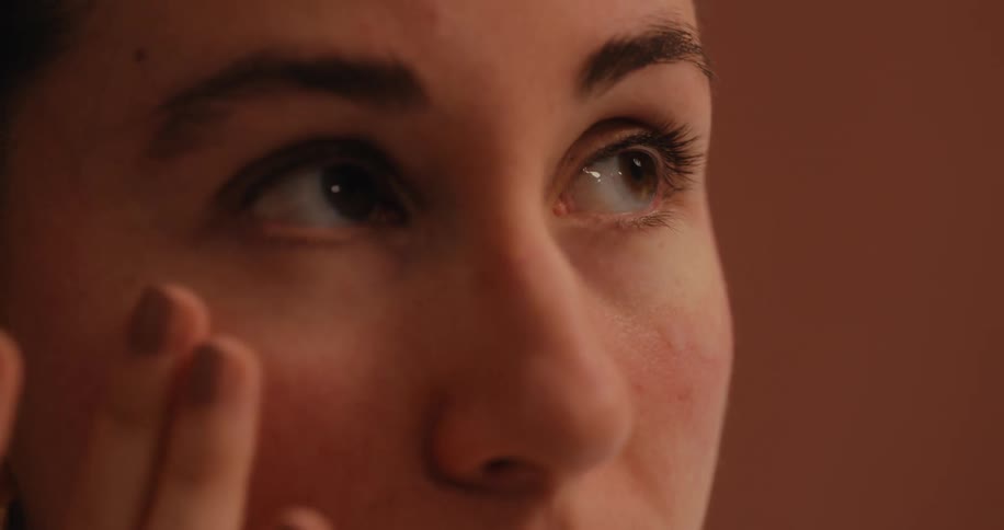 A woman applying cosmetic product to her cheek