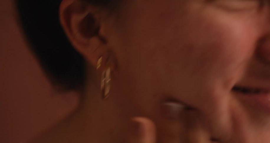 A woman smiling while applying a cosmetic product to her cheek and neck