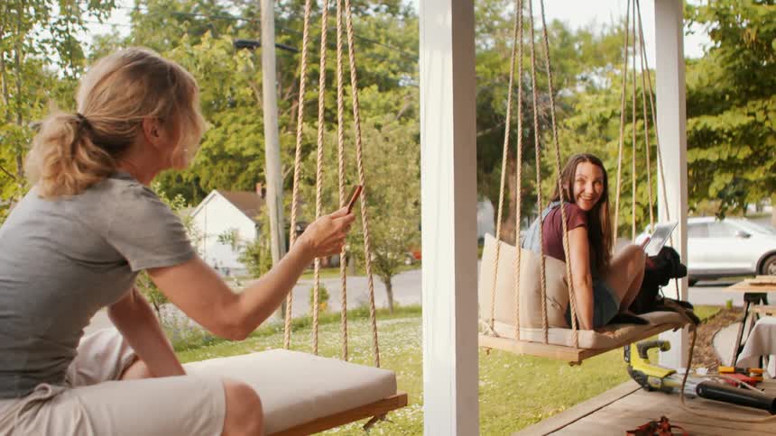 Two women sitting in a backyard talking and smiling