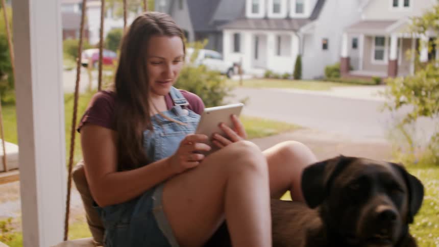 Two women are using their devices on the porch