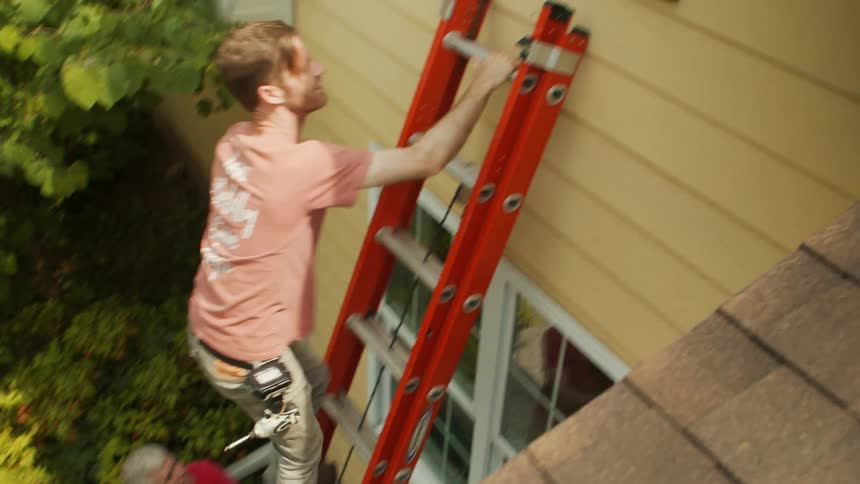 A man climbs a ladder up to the window
