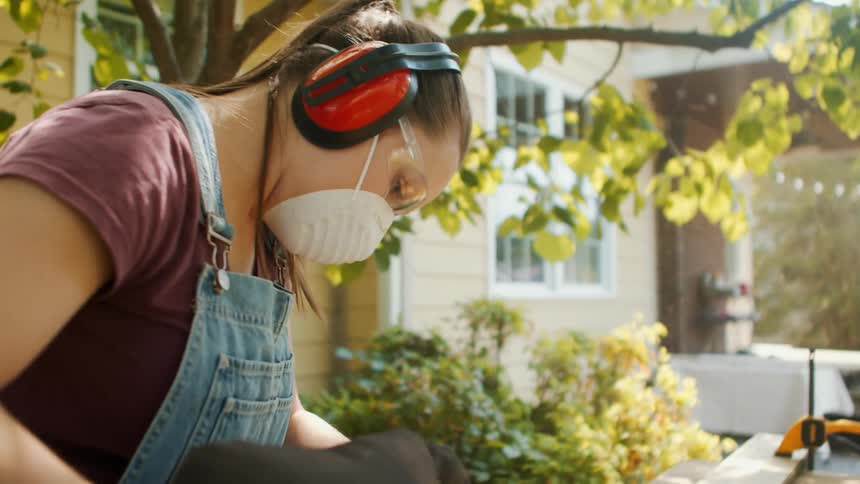 Man and woman in protective gear sanding wood with a power tool