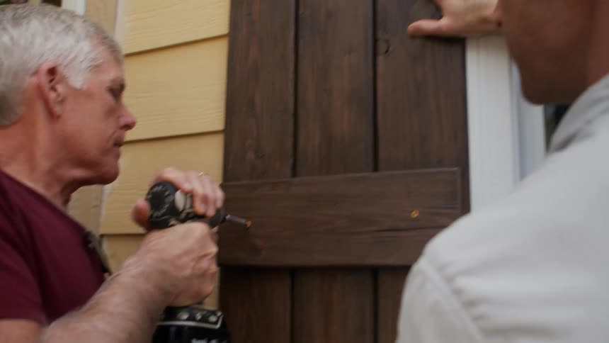 A man drills a wooden frame on the window