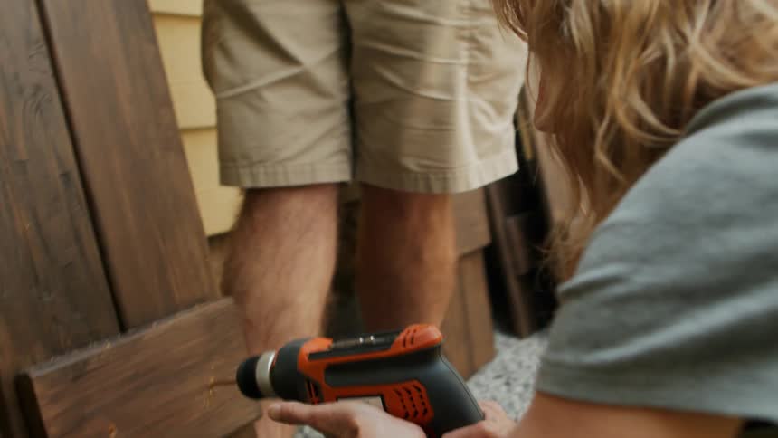 A woman drills a hole in wood