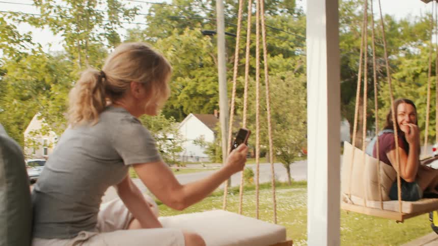 Two women are sitting on wrings on their porch