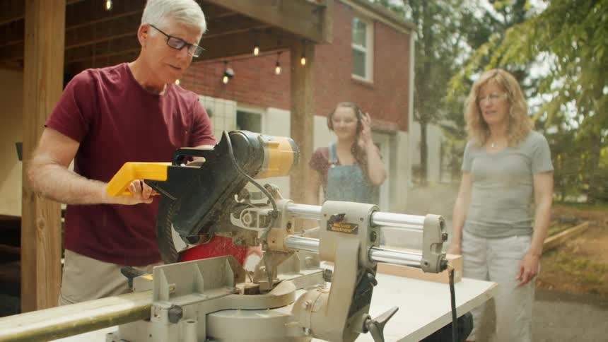 A man is cutting planks of wood with a table saw