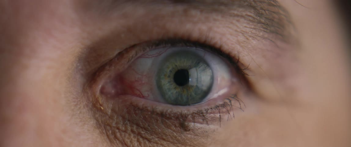 An eye slowly opening to reveal a blue green iris