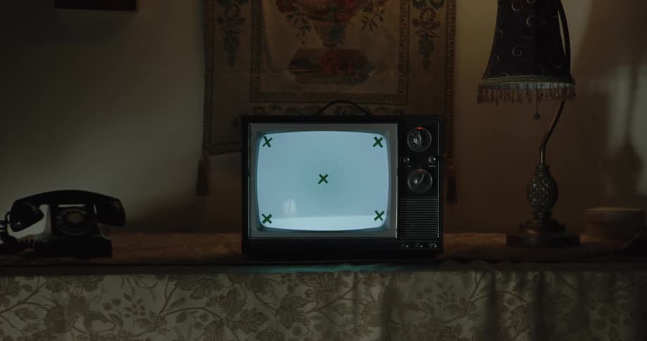 Television with no signal in the middle of a vintage telephone and a table lamp