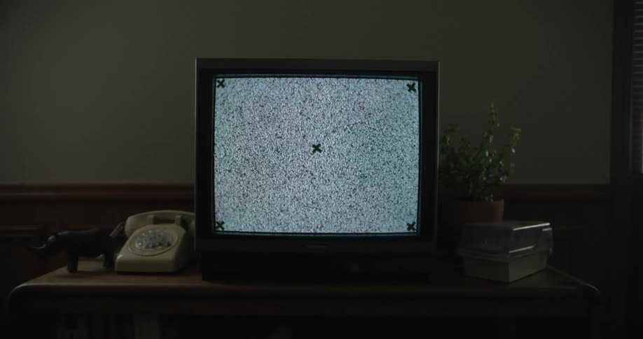 The television is flickering in the dark room