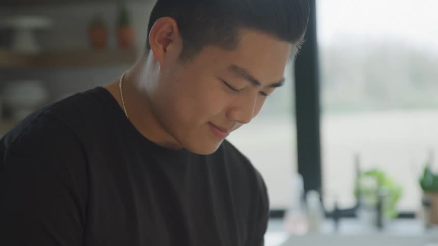 A man in a black shirt looks down and smiles at something