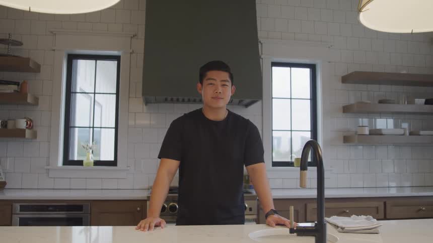 Young man with happy facial expression standing on a countertop in the kitchen