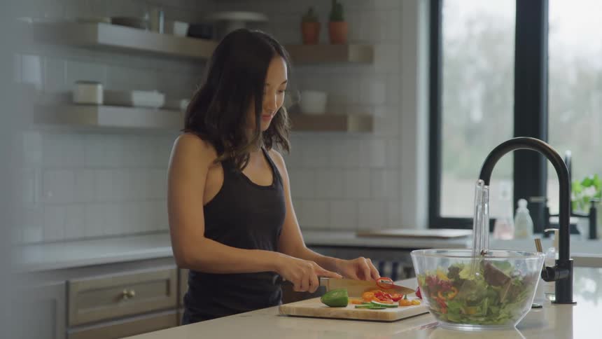 Woman cutting tomatoes on a wooden cutting board in the kitchen