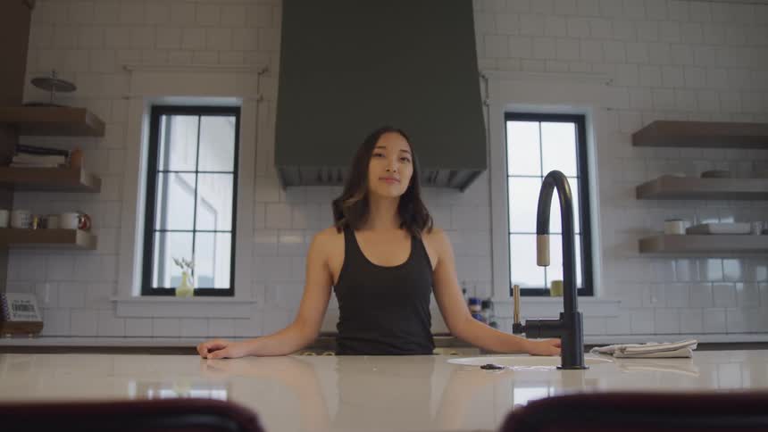 Woman smiles slightly while standing in her kitchen during the daytime
