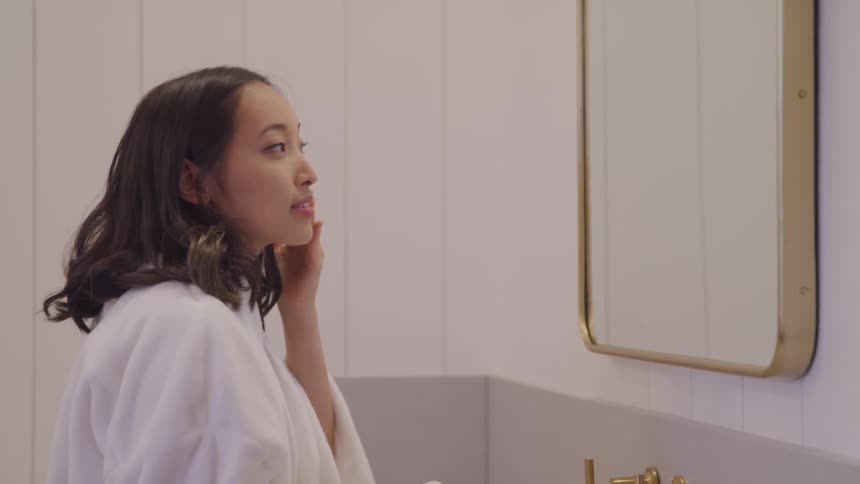 Woman in front of the mirror massaging her face