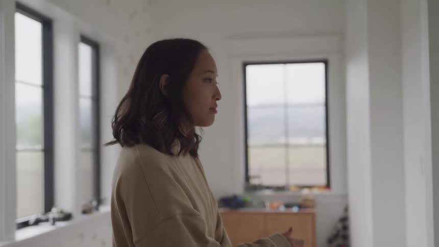 A woman walks through her home while holding her face