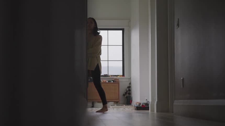 Woman walking down the hallway of the house with a thoughtful expression