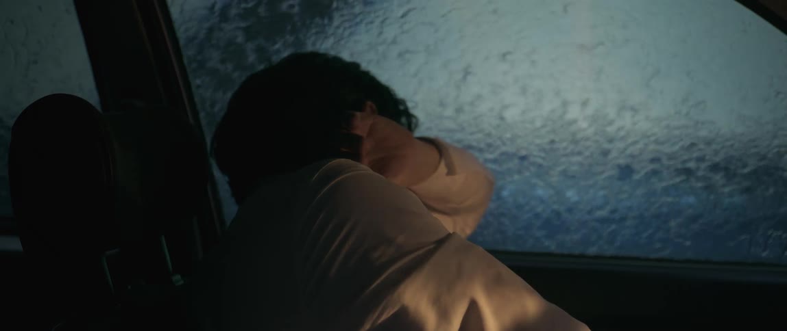 Man driving a car covers his face as tempered glass flies at him and water pours down his window