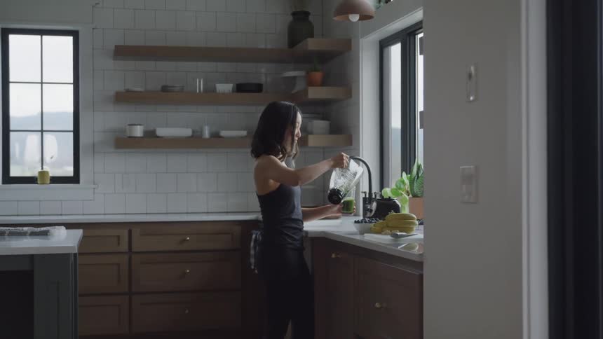 Woman in the kitchen drinking a green juice