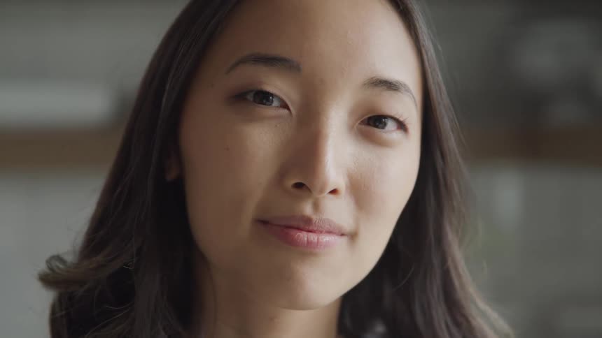 A woman blinks and then turns her head to lightly smile