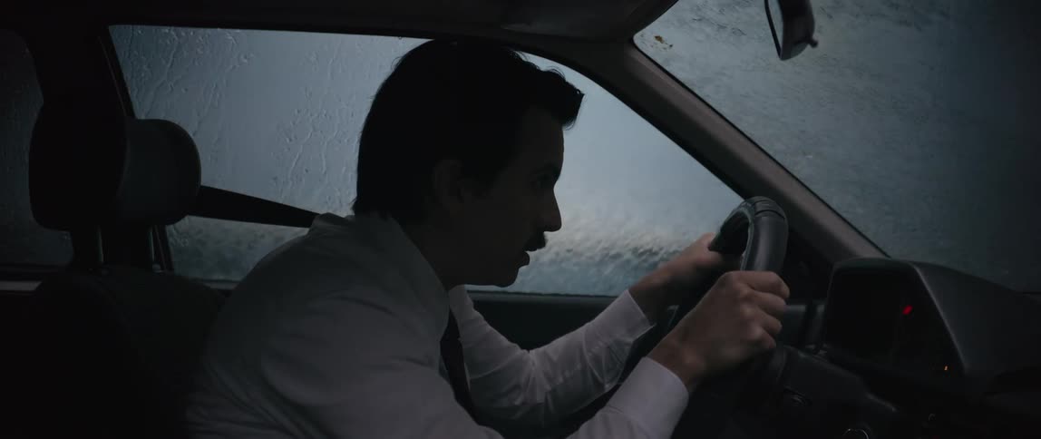 A man driving in the rain panics when he sees a light