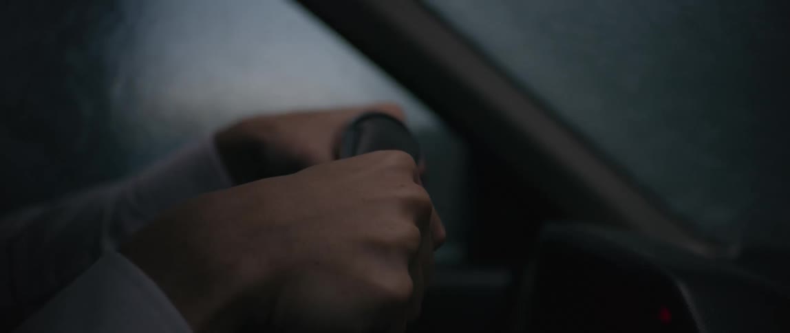 Pair of hands of a person on the steering wheel driving on a rainy day