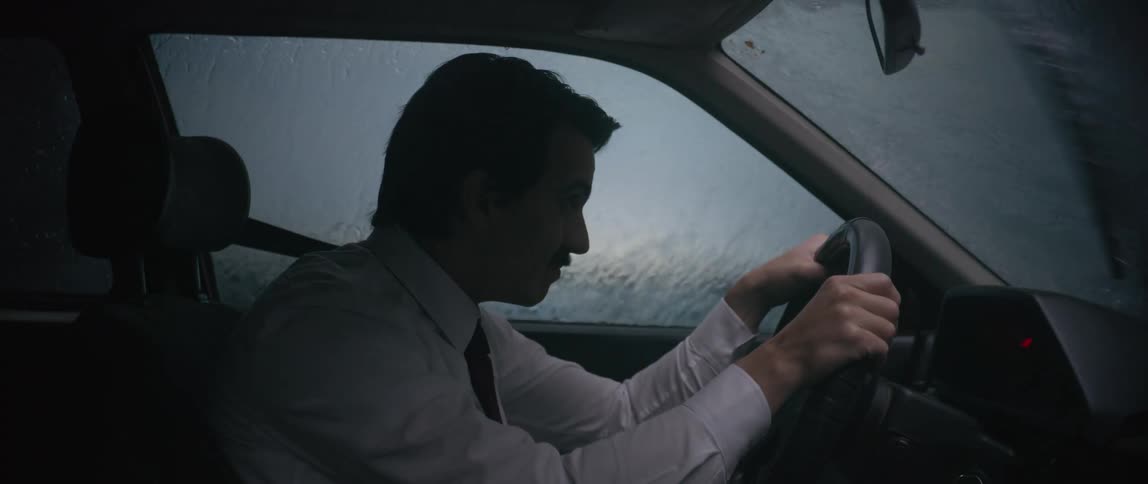 During a rain storm a man is carefully driving his car